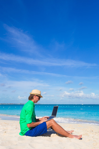 Young man with laptop on white tropical beach - Photo, Image