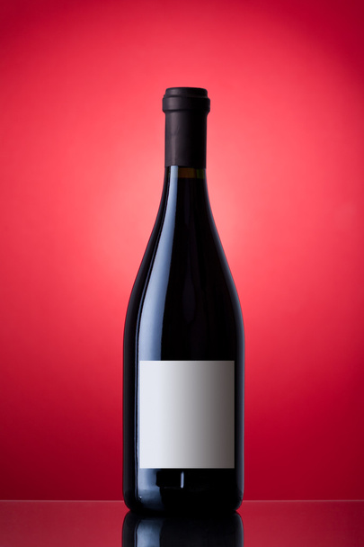Unopened wine bottle on a red background - Foto, Imagem