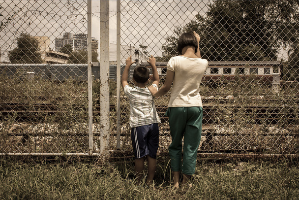 ασιατικό κορίτσι και αγόρι λυπημένος χέρι κρατούν φυλακή στο σιδηροδρόμου, σιδηροδρόμων Ηνωμένες - Φωτογραφία, εικόνα