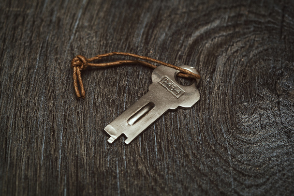 decorative vintage key on a rope on a wooden textured board - Fotografie, Obrázek
