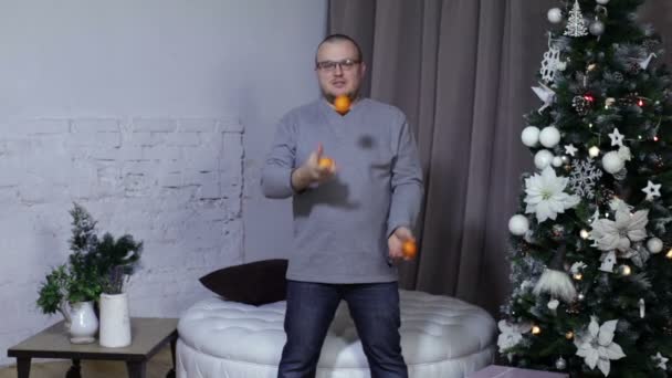 Man juggle mandarins near christmas tree - Filmagem, Vídeo