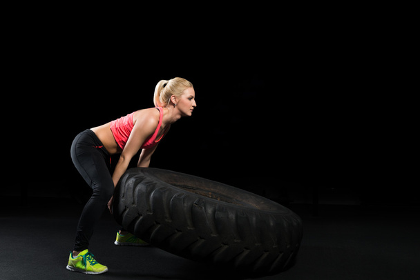 Muscular woman flip big tire as a part of Cross fit training. - Fotoğraf, Görsel