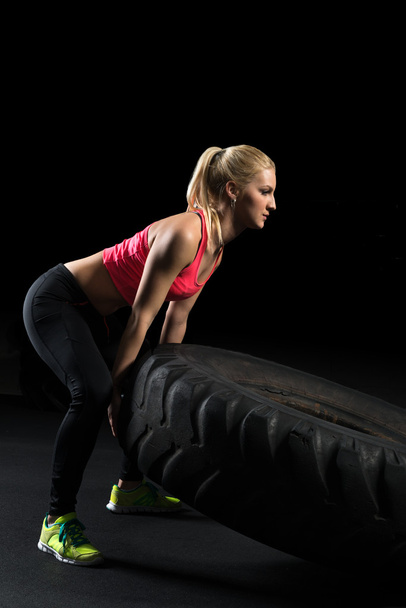 Muscular woman flip big tire as a part of Cross fit training. - Фото, изображение