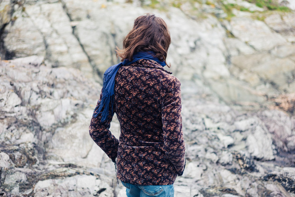 Young woman walking on the rocky coast - Fotoğraf, Görsel