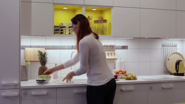 Μια γυναίκα που πλένει τα σταφύλια στο νεροχύτη της κουζίνας - Πλάνα, βίντεο