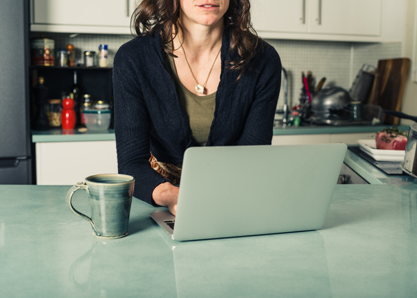 Young woman using laptop in kitchen - Фото, зображення