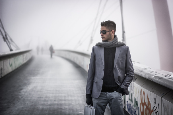 Handsome trendy man walking on a bridge in winter - Fotó, kép