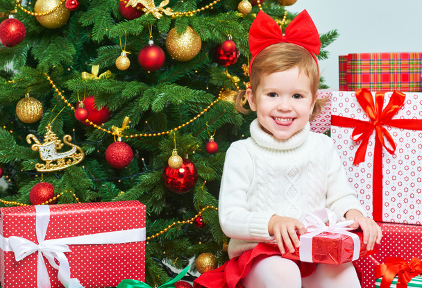 onnellinen lapsi joululahjoilla joulukuusen lähellä
 - Valokuva, kuva