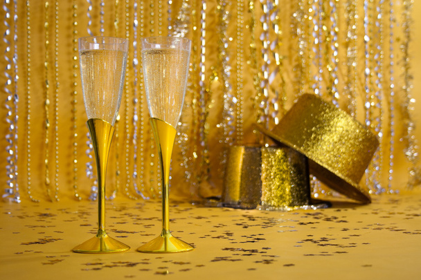 Dos flautas de champán de oro con sombreros de fiesta con lentejuelas
 - Foto, imagen