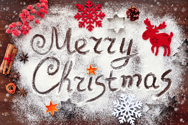 Merry Christmas text made with flour with decorations on cutting board - Фото, изображение