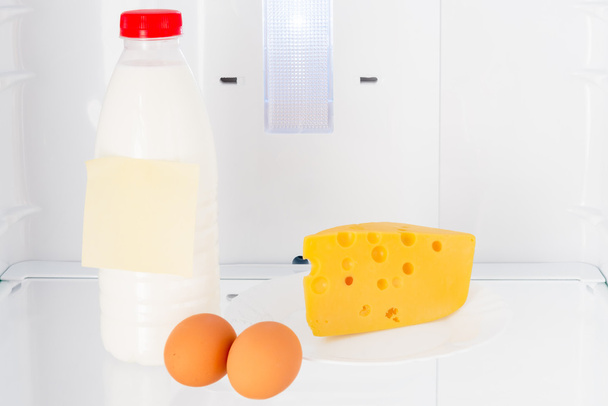 zuivelproducten en eieren op de plank van de koelkast - Foto, afbeelding