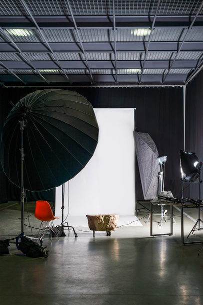 Lege fotostudio met modern interieur en verlichtingsapparatuur. Voorbereiding voor de studio schieten: lege stoel en studio verlichting. - Foto, afbeelding
