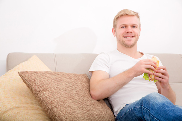 Young man eating a sandwich at home - Foto, imagen
