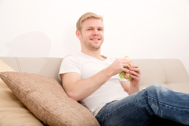 Joven comiendo un sándwich en casa
 - Foto, imagen