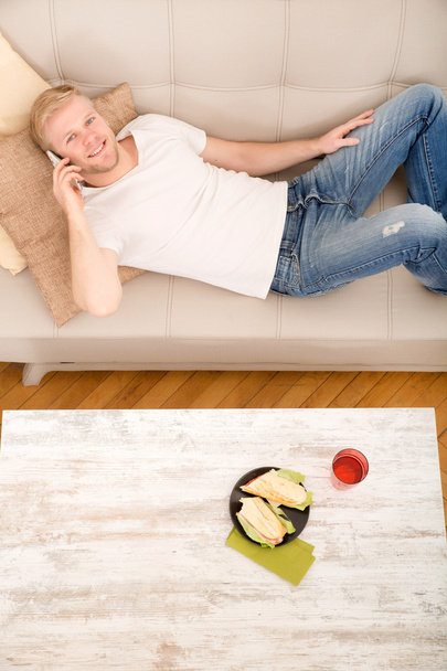 Young man with a Sandwich on the Sofa  - Foto, imagen