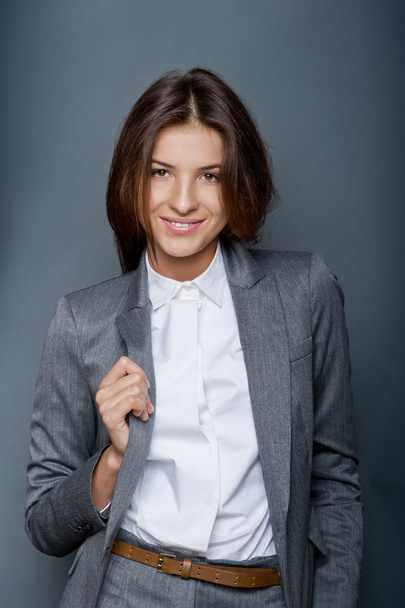 Portrait of a beautiful young business woman standing against grey backgrou - Fotó, kép