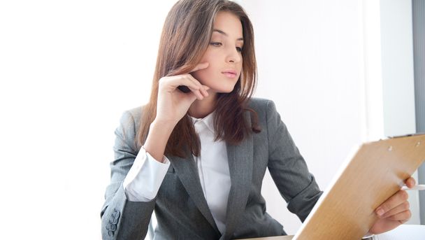 A portrait of a young business woman in an office with documents in her arm - Photo, image