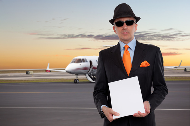 Business man next to a private jet holding a stack of papers - 写真・画像