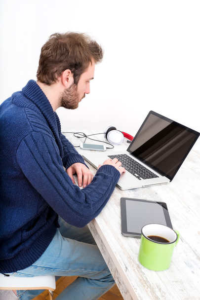 Jonge man thuis zijn laptopcomputer gebruikt - Foto, afbeelding