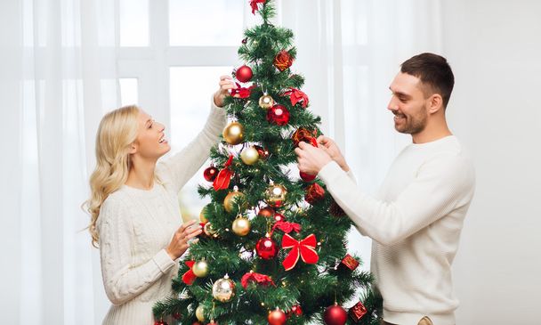 happy couple decorating christmas tree at home - Zdjęcie, obraz