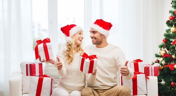 happy couple with christmas gifts and thumbs up - Foto, afbeelding