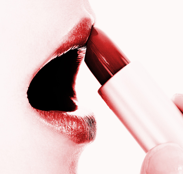 glanzende rode lippenstift op haar lippen toe te passen - Foto, afbeelding