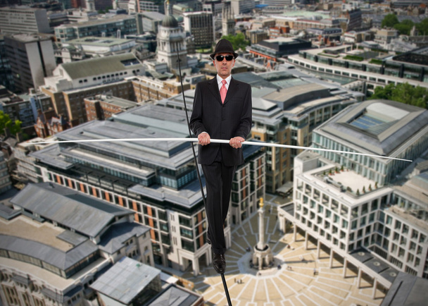 Ο άνθρωπος των επιχειρήσεων σε ισορροπία σε ένα σχοινί πάνω από μια πόλη - Φωτογραφία, εικόνα