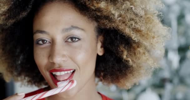 Young woman biting a festive candy cane - Metraje, vídeo