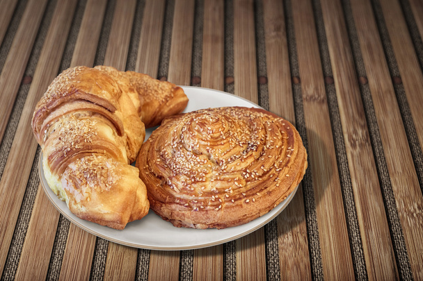 Croissant Puff Pastry Snail Rolls Sprinkled with Sesame Seeds on Bamboo Place Mat - Photo, Image