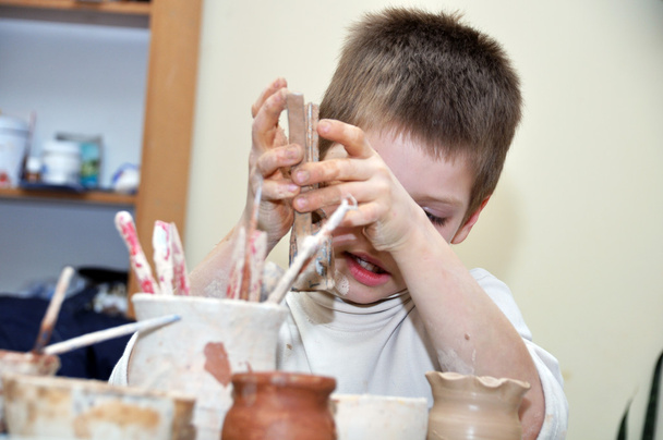 Child boy shaping clay in pottery studio - 写真・画像