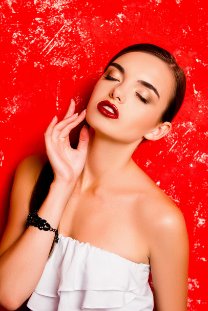 Cute girl touching her face against the red background  - Foto, Imagen