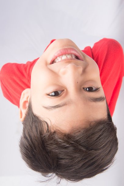 Маленький хлопчик дивиться вгору з посмішкою на білому тлі
 - Фото, зображення