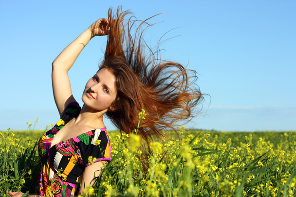 Beautiful young girl on the yellow meadow. Wind hair - Photo, Image