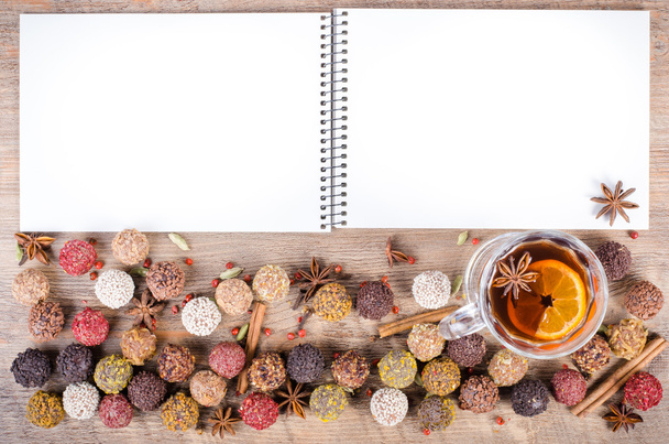 Handmade chocolate candies collection, dried oranges, cinnamon, cloves, cardamom, mulled wine, notebook on wooden background. Free space for your text. - Φωτογραφία, εικόνα