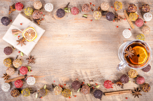Handmade chocolate candies collection, dried oranges, cinnamon, cloves, cardamom, mulled wine, notebook and pencil on wooden background. Free space for your text. - Foto, Imagem