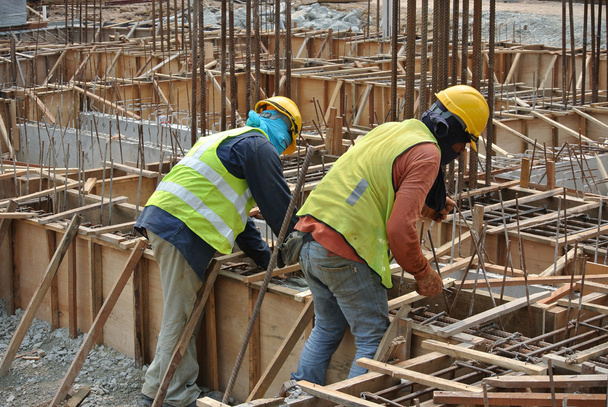 Groupe de travailleurs de la construction fabriquant des coffrages de poutres au sol
 - Photo, image