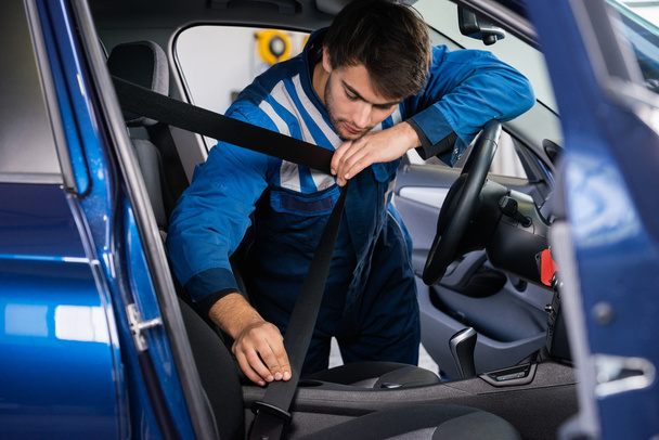 Mechanic testing car seat belt - Foto, afbeelding
