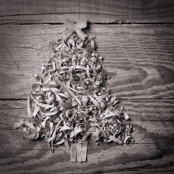 Simple Christmas tree arranged from sawdust, wood-chips on grey  - Photo, Image