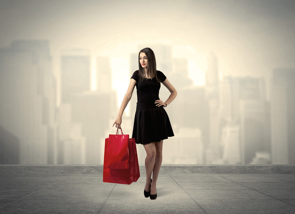 Κομψό κορίτσι της πόλης με κόκκινες τσάντες για ψώνια - Φωτογραφία, εικόνα