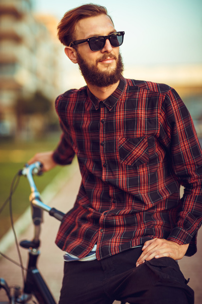 Man in sunglasses riding a bike on city street - Fotó, kép