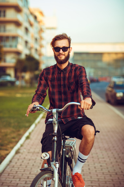Hombre con gafas de sol en bicicleta en la calle de la ciudad
 - Foto, imagen
