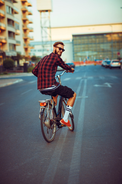Adam Bisiklete binmek şehir sokak güneş gözlüğü - Fotoğraf, Görsel