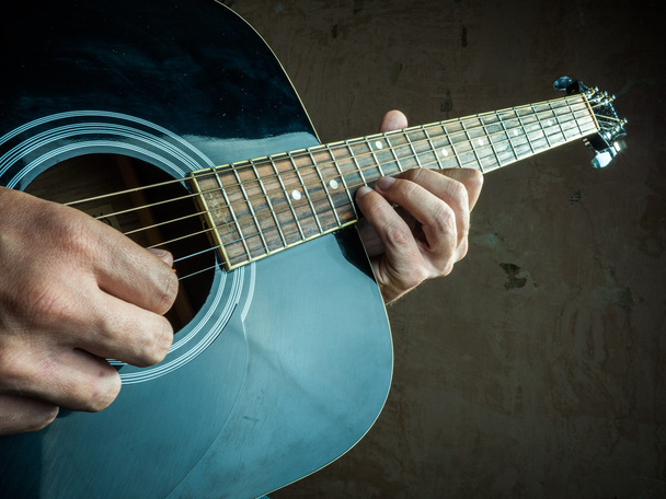 Closeup photo of an acoustic guitar played by a man. - Фото, изображение