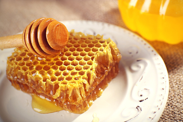 Honeycomb, dipper on white plate and pot of honey closeup - Foto, afbeelding