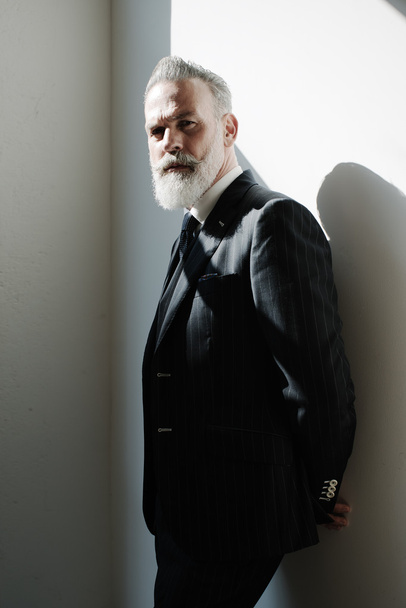 Stylish bearded man wearing trendy suit against a wall. - Foto, afbeelding