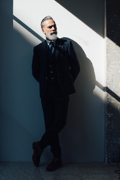 Stylish bearded man wearing trendy suit and stands against the wall - Fotografie, Obrázek
