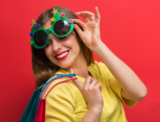 Donna con occhiali da festa di Natale e borse della spesa
 - Foto, immagini