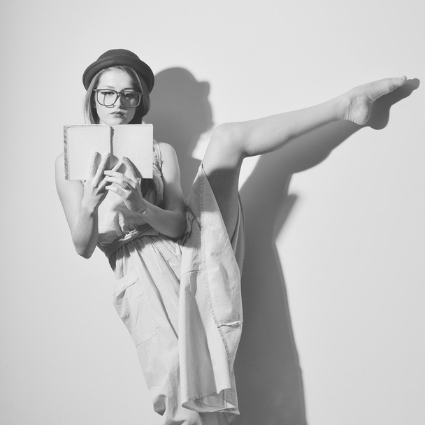 Portrait of elegant gymnast in a hat and glasses reading a book - Foto, afbeelding