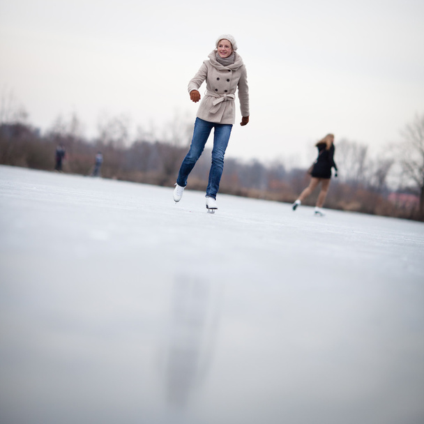 Young woman ice skating outdoors on a pond - Φωτογραφία, εικόνα