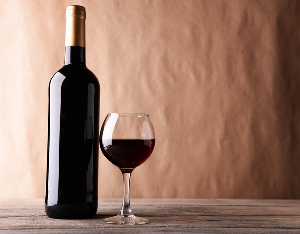 A bottle of red wine and a glass on wooden table - Photo, Image